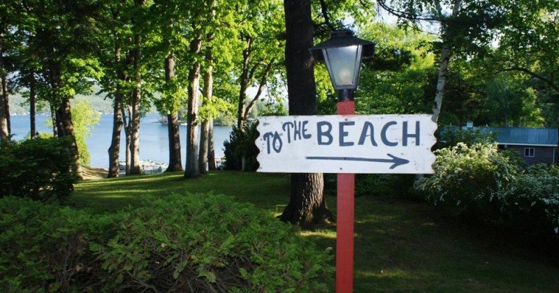 Sign in front of the lake & trees. Text: To The Beach arrow.