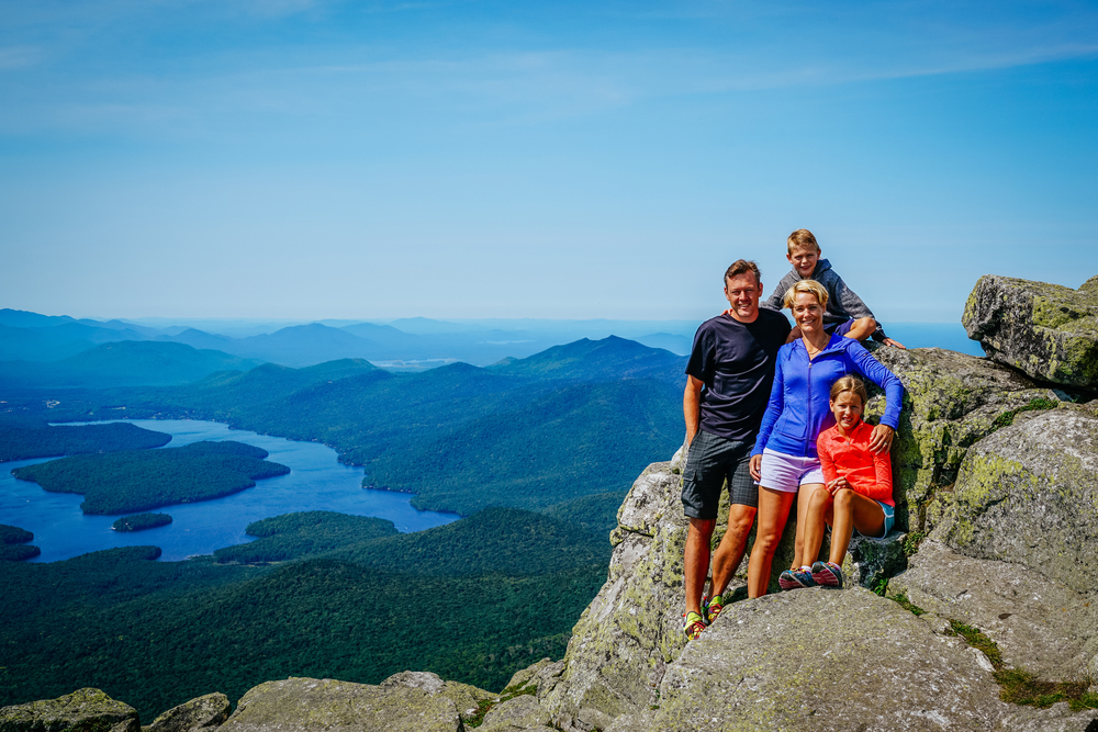 Family posing on a rocky mountain overlooking a valley and river