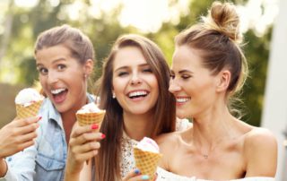A group of three women enjoy a summer in Lake George, holding ice cream cones.