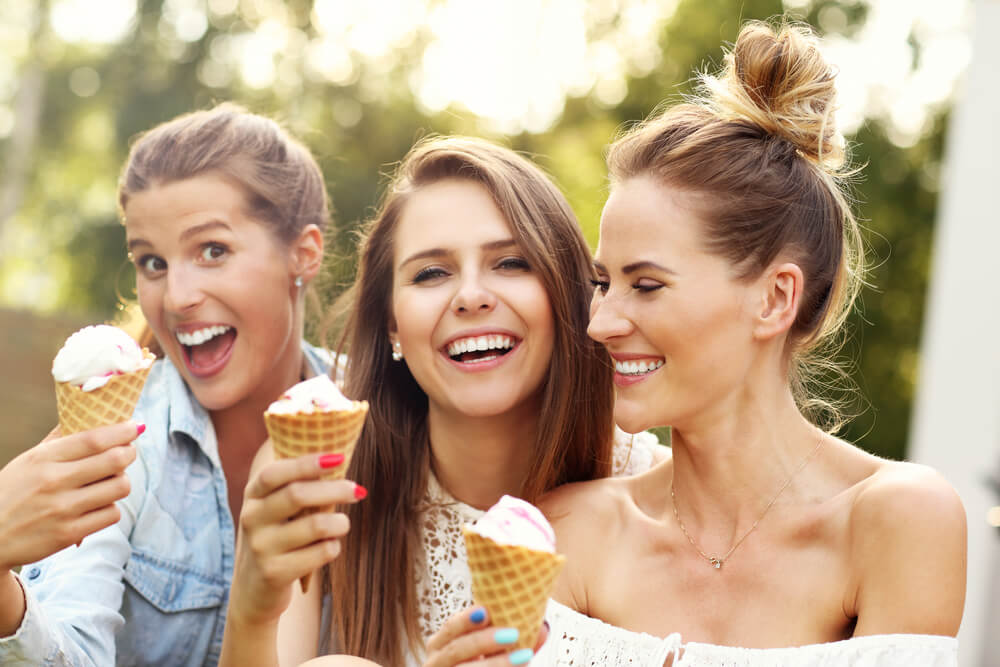 A group of three women enjoy a summer in Lake George, holding ice cream cones.